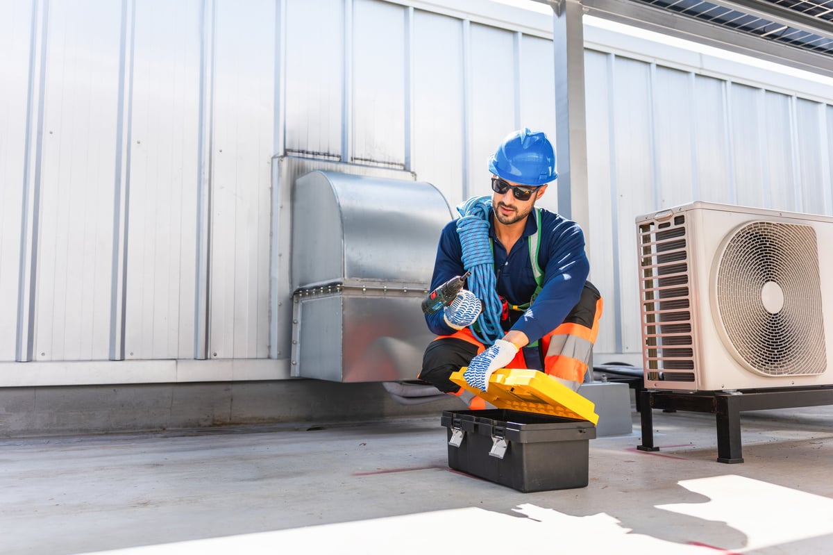Technician man taking electric drill from toolbox for hvac maintenance, Maintenance worker preparing tools on rooftop, Service engineer in safety gear repairing industrial air conditioning unit